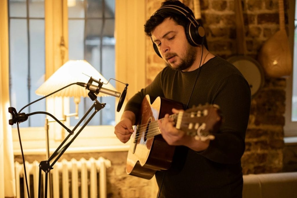 Guitariste en train d'enregistrer sa guitare acoustique en home studio