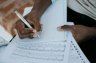 Pour comprendre comment lire une tablature guitare, un musicien note des indications au stylo sur un cahier posé sur une partition avec tablature